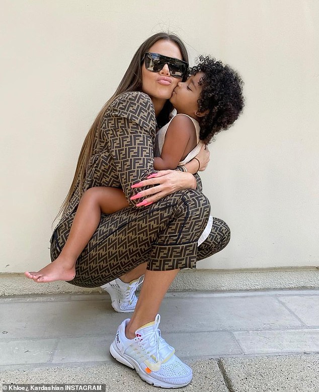 Special moments: The 36-year-old crouched down with her three-year-old on her lap, hugging and kissing the adorable tot while posing in a Fendi two-piece outfit